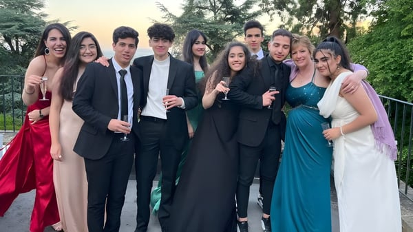 Un grupo de estudiantes del Abbey College posan formalmente al aire libre frente a árboles y áreas verdes.