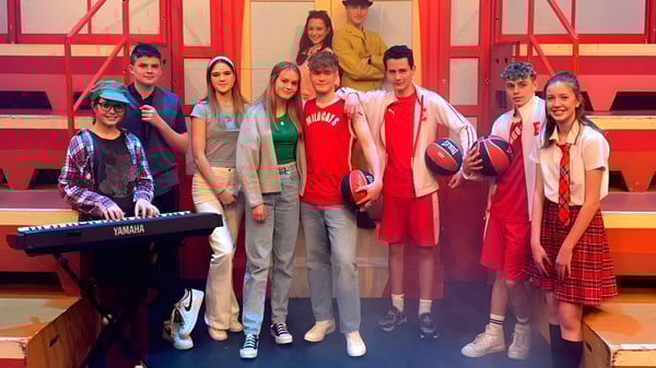 Un grupo de estudiantes está junto frente a un fondo rojo-naranja en el campus de la Abbotsholme School.