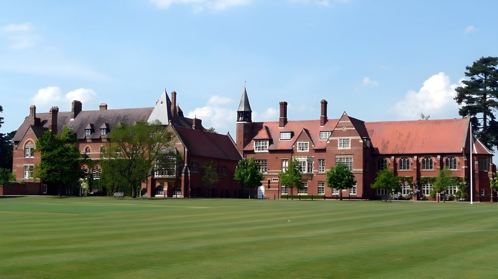 El histórico edificio de ladrillo con varias chimeneas y un césped verde delante en el terreno de la Abingdon School.