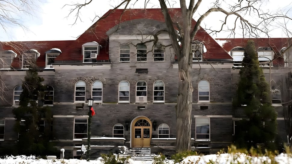 El histórico edificio de ladrillo de la Academy of the New Church está rodeado de árboles cubiertos de nieve.