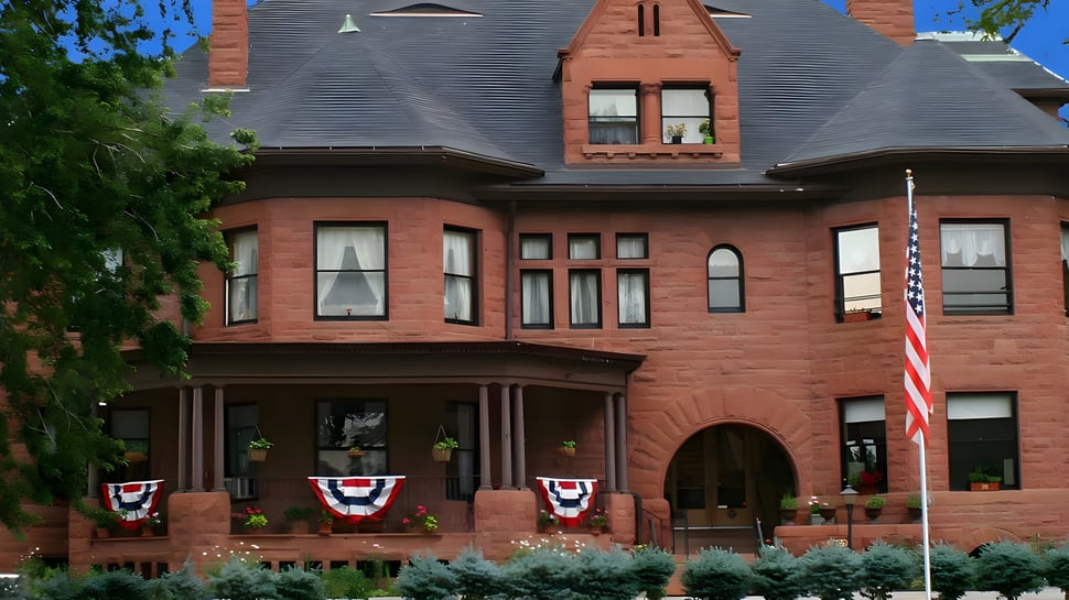 El histórico edificio de ladrillo de la Accelerated School está rodeado de vegetación verde y decorado con adornos patrióticos.