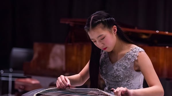 Una estudiante del ACG Parnell College toca concentrada un instrumento musical bajo la iluminación del escenario.