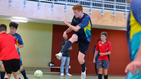Un niño jugando al fútbol en el gimnasio del campus de ACG Tauranga.