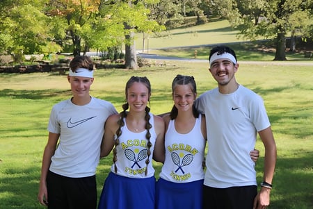 Un grupo de cuatro personas está de pie juntas en un parque en el terreno de la Acorn High School.