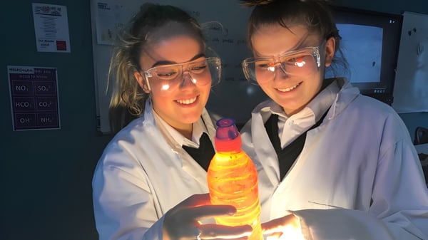 Dos estudiantes de la Adcote School en el laboratorio sostienen un objeto amarillo brillante durante el experimento.