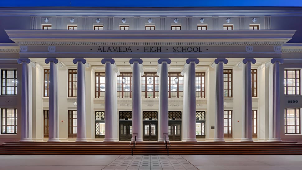El edificio principal neoclásico de la Alameda High School se puede ver iluminado por la noche.