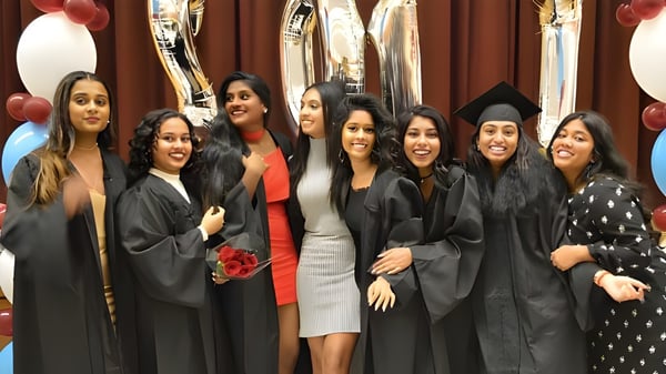 Un grupo de jóvenes mujeres en togas de graduación posando durante la ceremonia de graduación en el Albert Campbell Collegiate Institute.