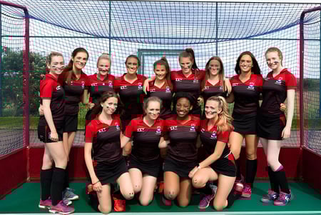 Un grupo de jóvenes atletas de la Albyn School posan juntas en un campo deportivo con una red al fondo.