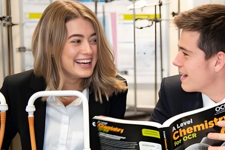 Dos estudiantes de la Aldenham School conversan animadamente mientras sostienen libros de texto.