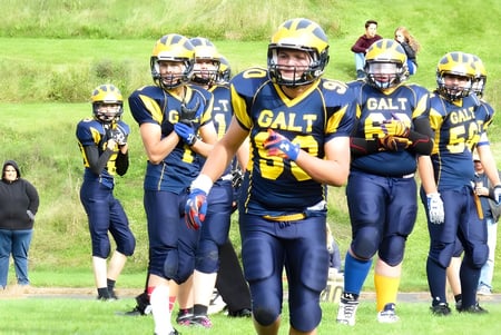 Un grupo de jóvenes futbolistas está de pie en el campo de césped de la Alexander Galt Regional High School.