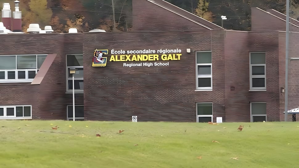 El gran edificio de ladrillo de la Alexander Galt Regional High School está rodeado de un prado con hojas de otoño.
