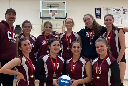Un grupo de jóvenes atletas femeninas está en el gimnasio de la Alexander Mackenzie High School frente a una canasta de baloncesto.