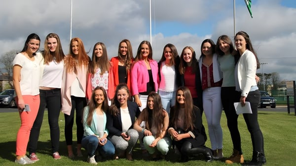 Un grupo de estudiantes se encuentra en un prado en el exterior del Alexandra College bajo un cielo nublado.