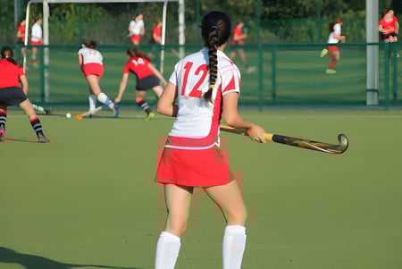 Una joven atleta sostiene un stick de hockey en el campo deportivo del Alexandra College.