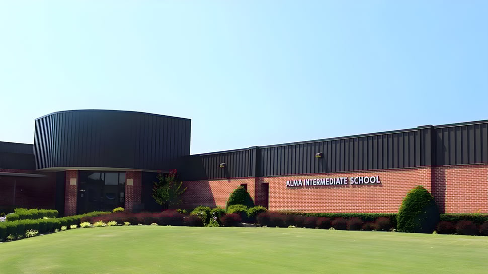 El moderno edificio de ladrillo de la Alma High School con techo curvado y un exterior bien cuidado.