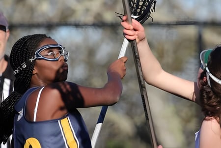 Dos estudiantes de Annie Wright Schools juegan lacrosse en el campo.