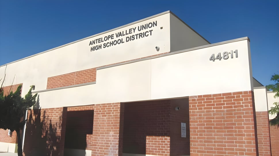 El gran edificio del Antelope Valley Union High School District de ladrillo y concreto frente a un cielo azul claro.