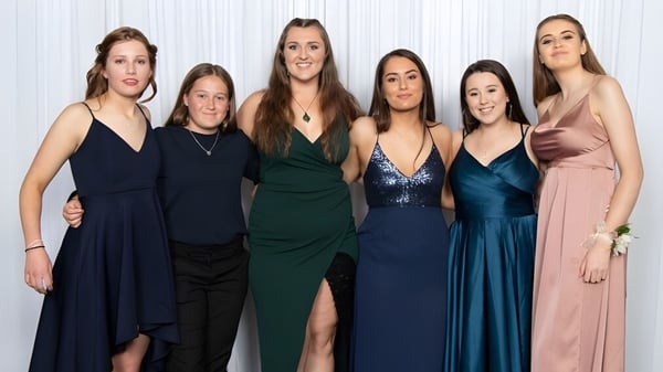Un grupo de seis estudiantes en diferentes vestidos de noche en el campus del Aotea College frente a un fondo blanco.