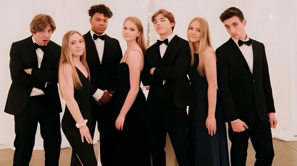 Un grupo de personas vestidas formalmente posan juntos en el edificio de la Arcadia High School.