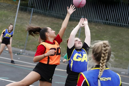 Dos alumnas de la Archbishop's School juegan un partido de netball en el campo de la escuela.