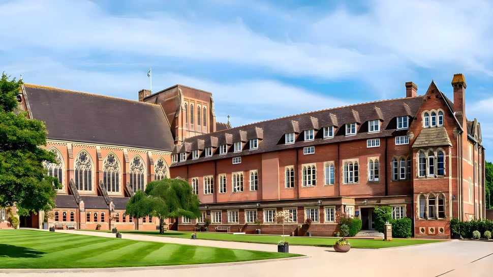 El edificio histórico de ladrillo con elaborados detalles arquitectónicos en el campus del Ardingly College está rodeado de césped bien cuidado y árboles verdes.