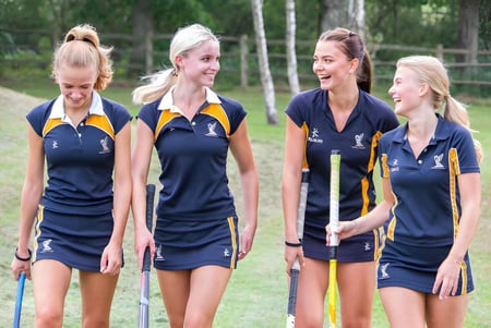 Cuatro alumnas del Ardingly College están juntas en una zona cubierta de hierba en el bosque.