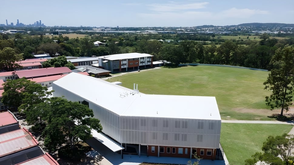 Un gran campo de césped con árboles y un edificio moderno en el campus de la Ardscoil Mhuire.
