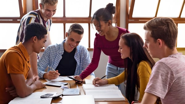 Un grupo de estudiantes de Ardscoil Phadraig discute y trabaja juntos en una mesa.