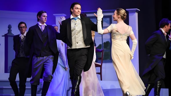 Estudiantes y profesores de la Arendell Parrott Academy están en el escenario durante un evento formal bajo luces azules.