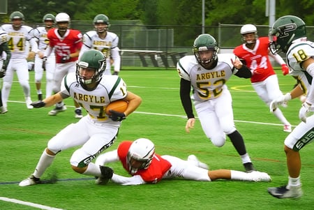 Estudiantes de la Argyle Secondary School juegan un partido de fútbol y realizan un tackle en el campo durante el juego.