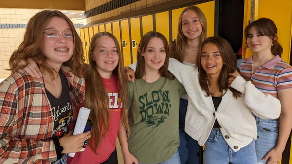 Un grupo de jóvenes estudiantes está junto en el pasillo de la Arizona Lutheran Academy con casilleros al fondo.