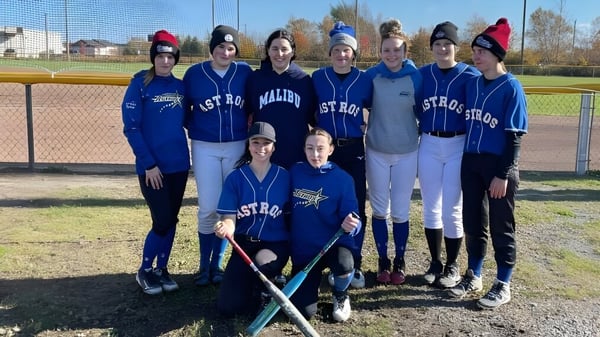 Un grupo de jóvenes atletas está de pie en uniformes azules juntos en el campo de béisbol de la Ascension Collegiate.