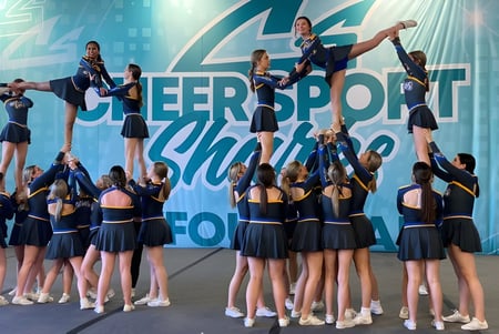 Un grupo de animadoras de la Ascension Collegiate realiza una rutina acrobática en la presentación de Cheersport Showdown en el escenario.