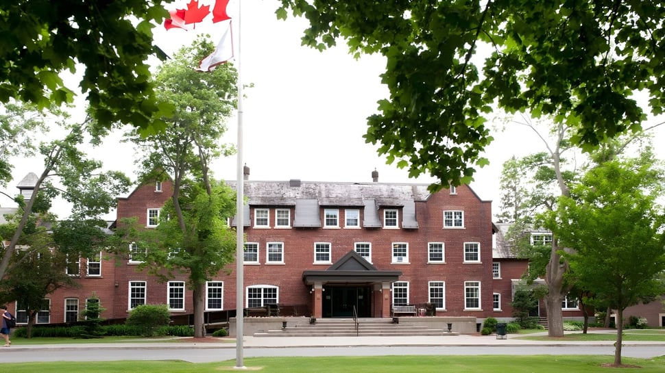 El edificio de ladrillo con una entrada distintiva y la bandera canadiense en el campus del Ashbury College.