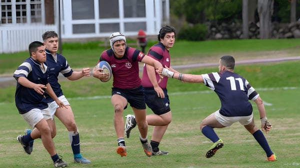 Estudiantes del Ashbury College juegan un partido de rugby en el campo frente a los edificios escolares.