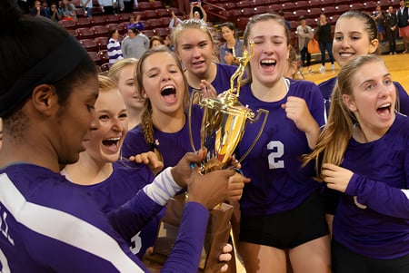 Las estudiantes de la Ashley Hall School celebran con un trofeo en el gimnasio después de una victoria en voleibol.
