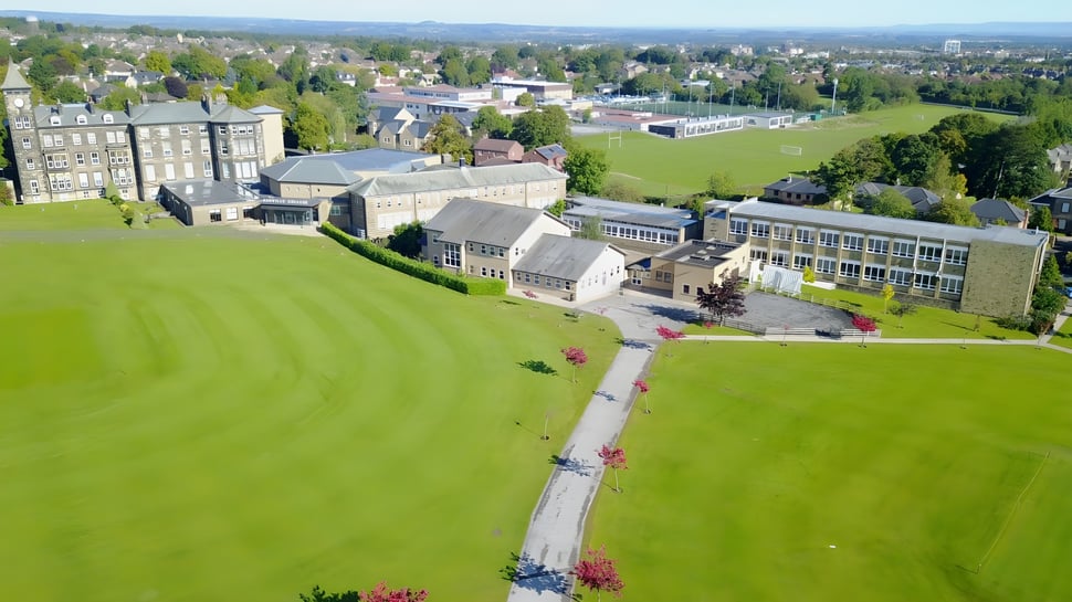 El campus del Ashville College está rodeado de un exuberante verde con un camino curvado entre edificios históricos y modernos.