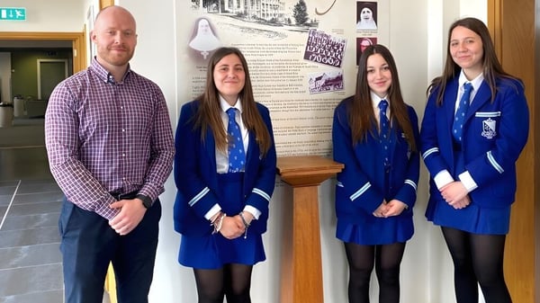 Un grupo de estudiantes está en el pasillo de la Assumption Grammar School frente a un tablón de anuncios.