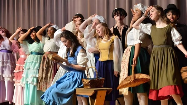 Un grupo de mujeres con coloridos vestidos retro posan en el escenario de la Atlantic Shores Christian School.