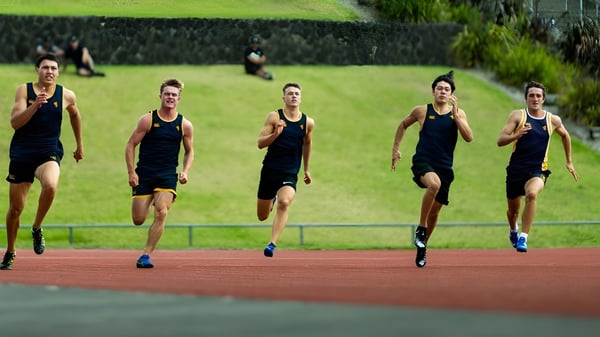 Un grupo de atletas en uniformes negros corre en la pista de la Auckland Grammar School.