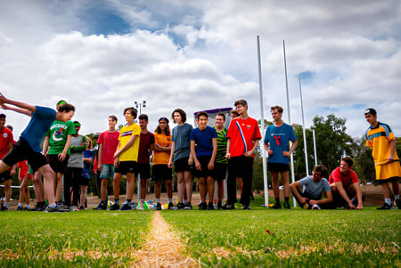 Un grupo de jóvenes atletas está de pie en un campo cubierto de hierba en el campus de la Australian Science and Mathematics School.