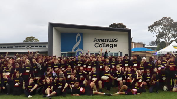 Un gran grupo de estudiantes está frente al edificio del Avenues College.