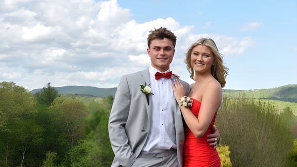 Una joven pareja se encuentra en un paisaje verde frente a montañas en el terreno de la Avon Old Farms School.