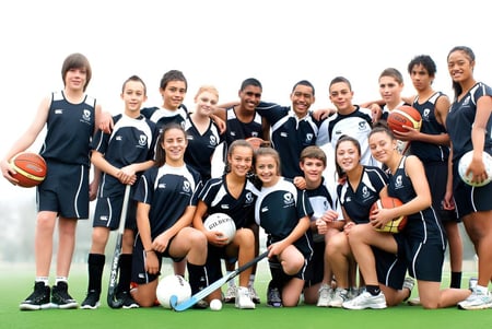 Un grupo de jóvenes deportistas está en un campo de hierba y posan juntos en el campus del Avondale College.