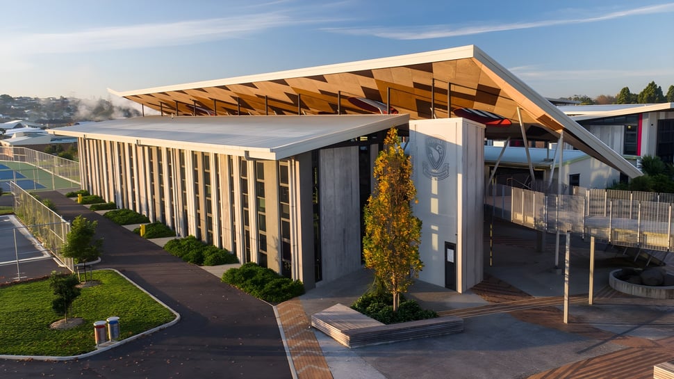 El moderno edificio del Avondale College con una destacada estructura de techo de madera se encuentra en un cuidado parque.