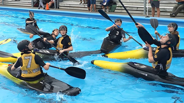 Estudiantes del Awatapu College participan en una actividad acuática con botes inflables amarillos en la piscina.