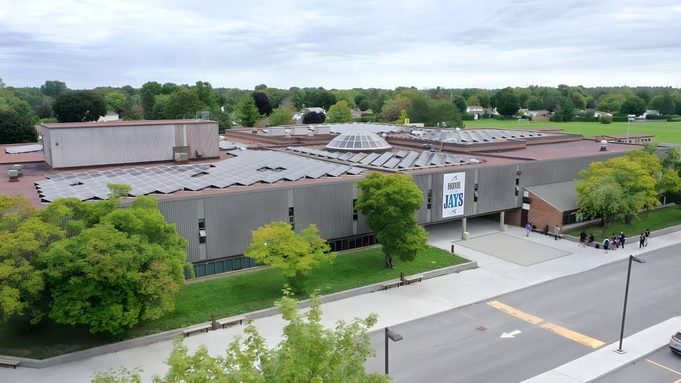 El moderno edificio principal de la A.Y. Jackson Secondary School está rodeado de un paisaje verde y árboles.