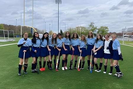 Un grupo de estudiantes en uniformes se encuentra en el campo de fútbol de la A.Y. Jackson Secondary School con el paisaje urbano de fondo.