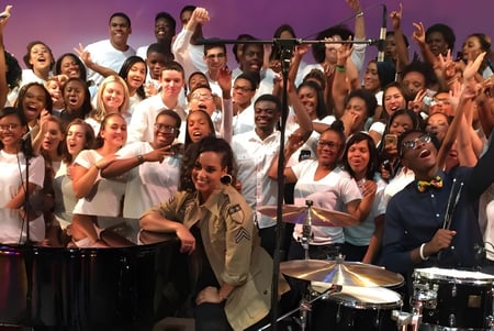 Estudiantes de la Balla Secondary School tocan juntos en el escenario frente a un fondo violeta instrumentos musicales.