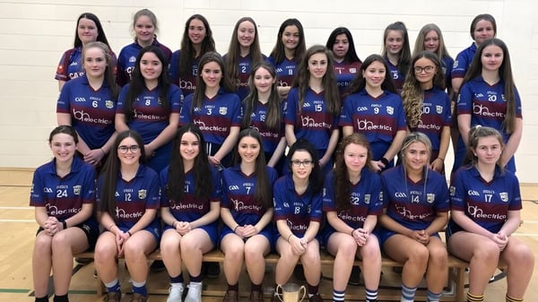 Un grupo de alumnas de la Ballingarry Presentation School posan en uniformes deportivos en un gimnasio.